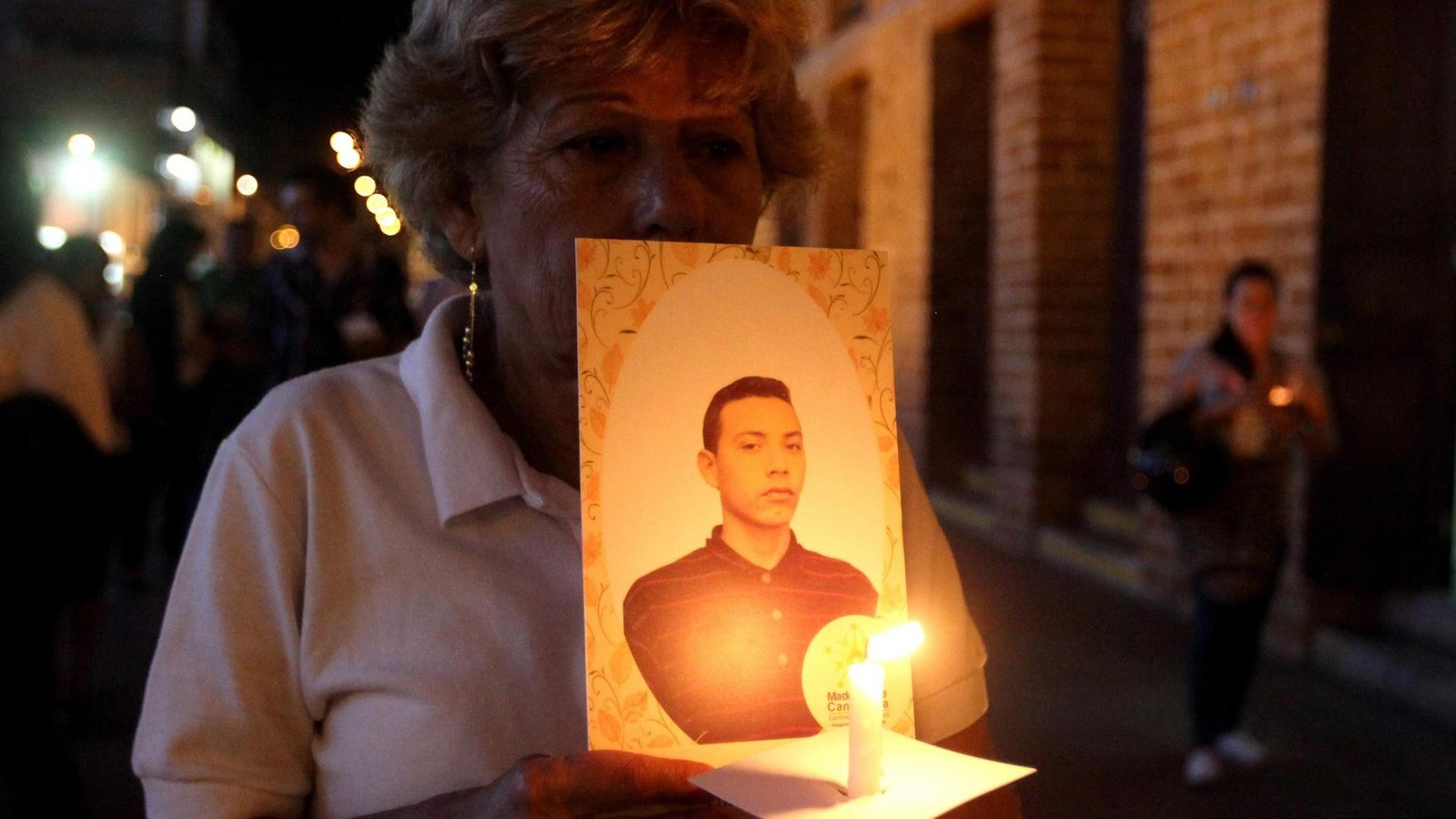 Ein Mitglied der "Madres de la Candelaria" in Medellín, Kolumbien, hält ein Foto ihres verschwundenen Angehörigen und eine Kerze in der Hand