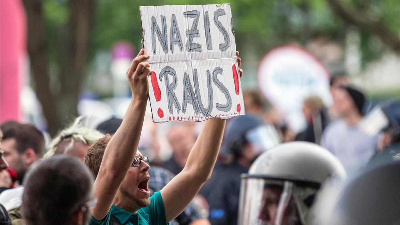 Ein Demonstrant hält in Berlin ein Plakat mit der Aufschrift "Nazis raus!" hoch.