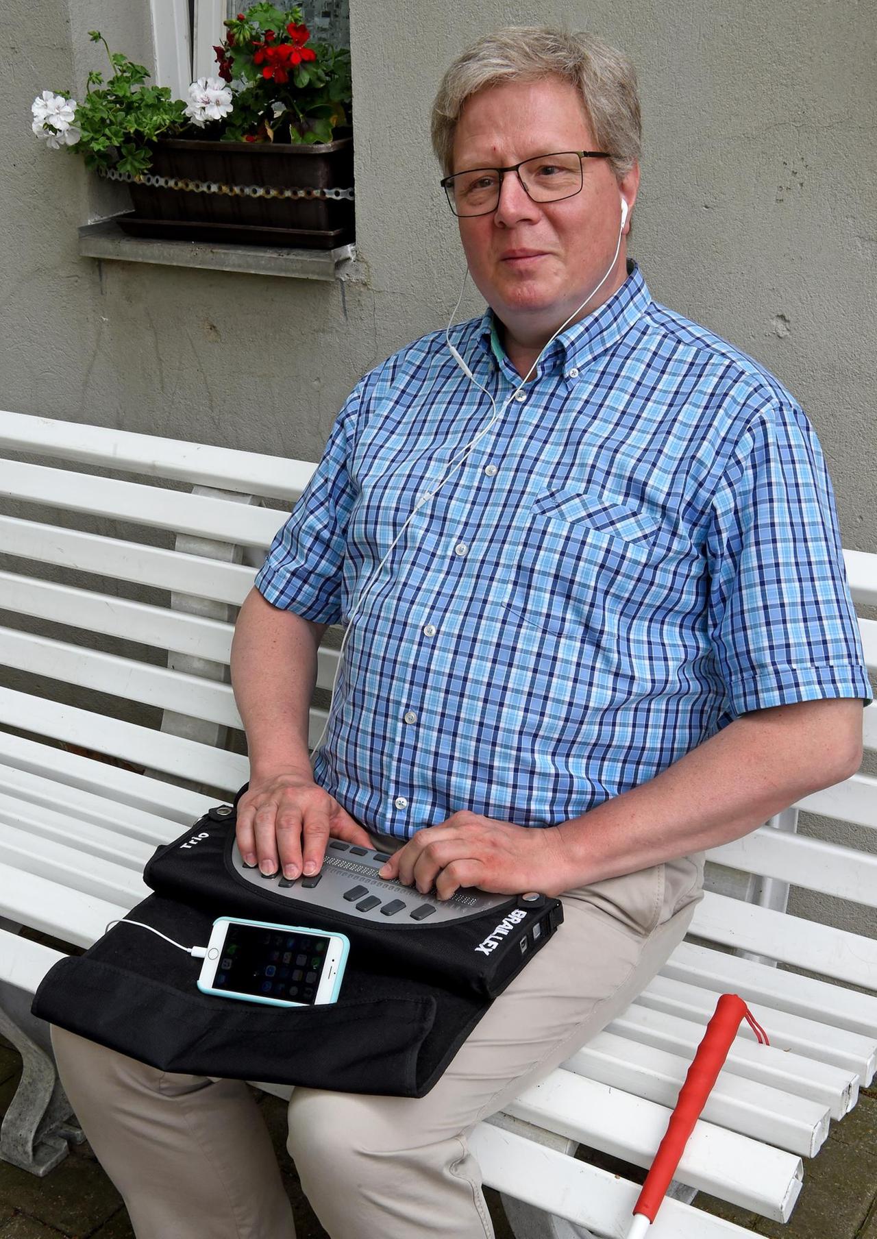 Thomas Kahlisch, Präsidiumsmitglied des Deutschen Blinden- und Sehbehindertenverbandes (DBSV), bedient sein Smartphone mit einer Braillezeile

