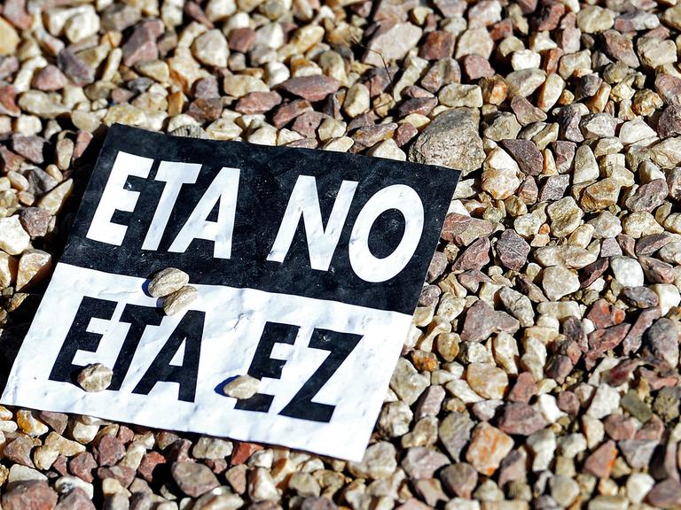 "ETA nein" auf Spanisch und auf Baskisch steht auf einem Aufkleber, der auf Kieselsteinen liegt