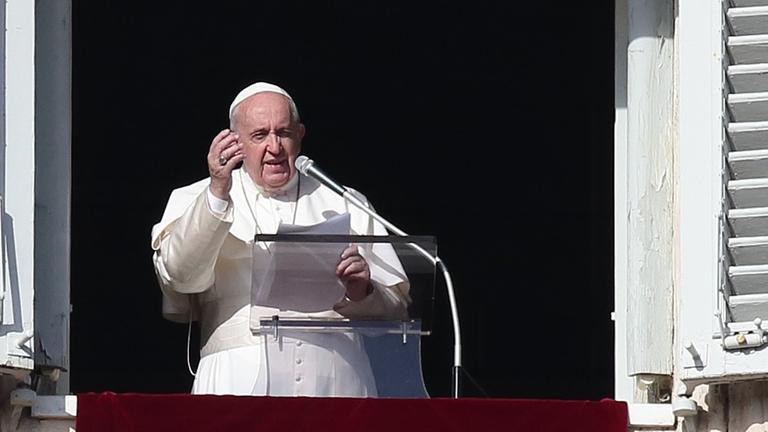 Papst Franziskus während des Angelus-Gebets auf dem Petersplatz. Er steht am offenen Fenster und hebt die rechte Hand.