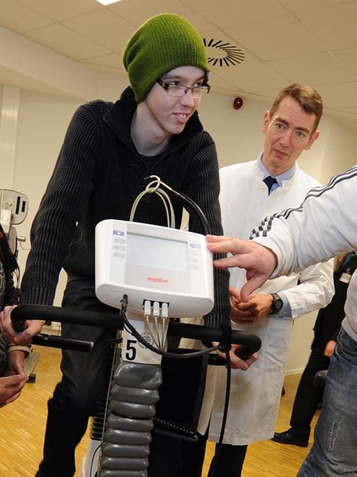 Der an Krebs erkrankte Fabian (m.) fährt auf einem Fahrradergometer in der Medizinischen Hochschule Hannover.