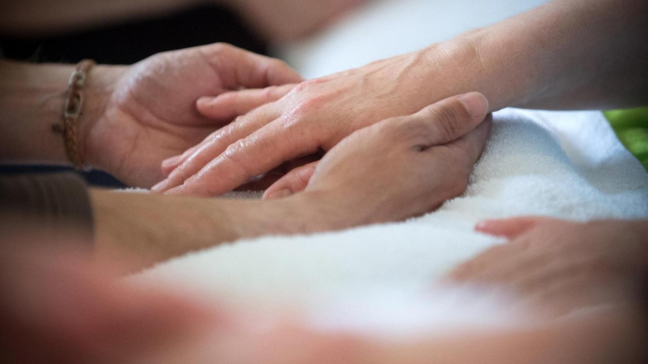 Intensives Berühren und Streicheln der Hände eines alten Menschen.
