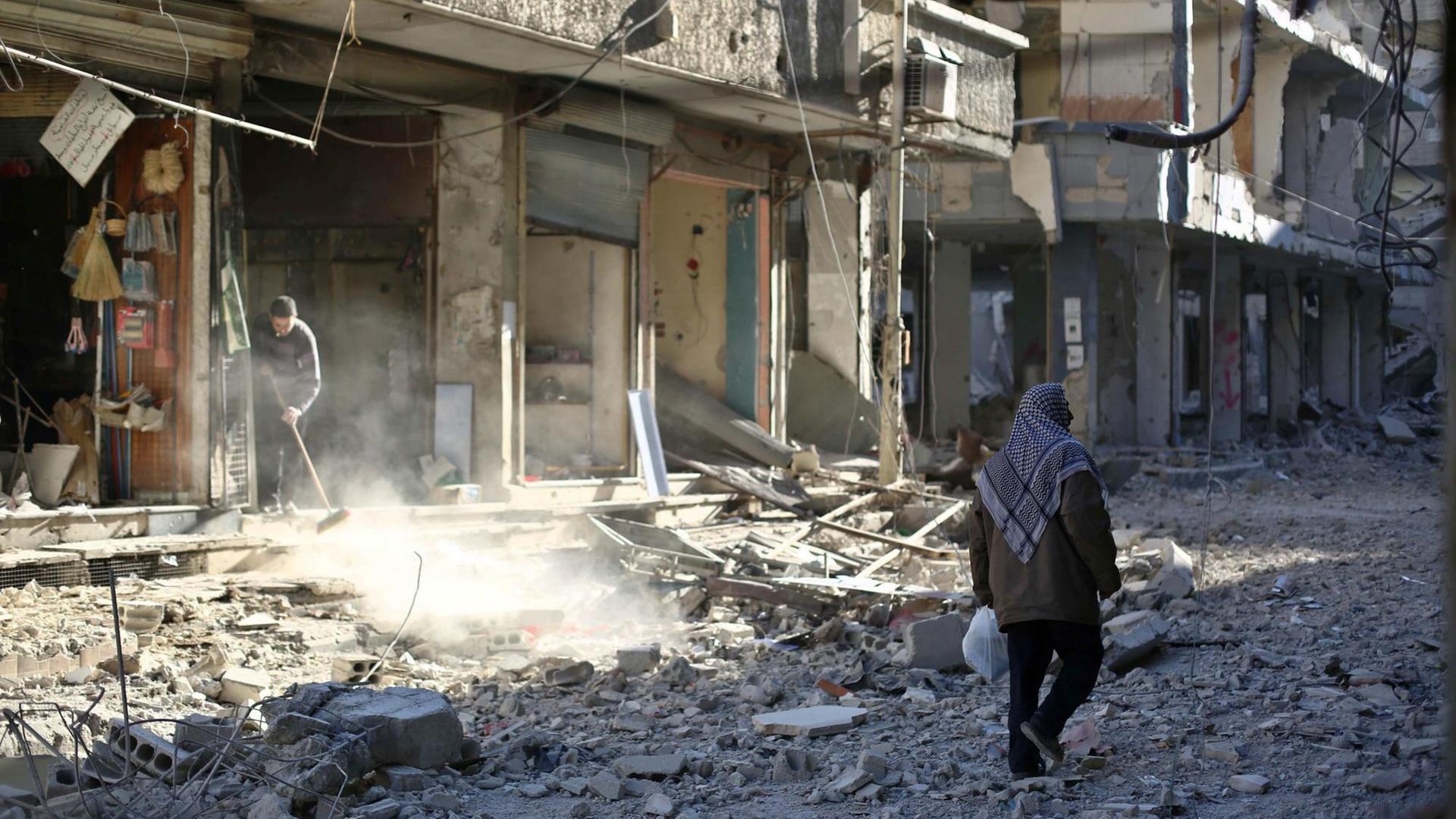 Ein Mann läuft durch eine Straße in der syrischen Stadt Duma, die voller Schutt ist.