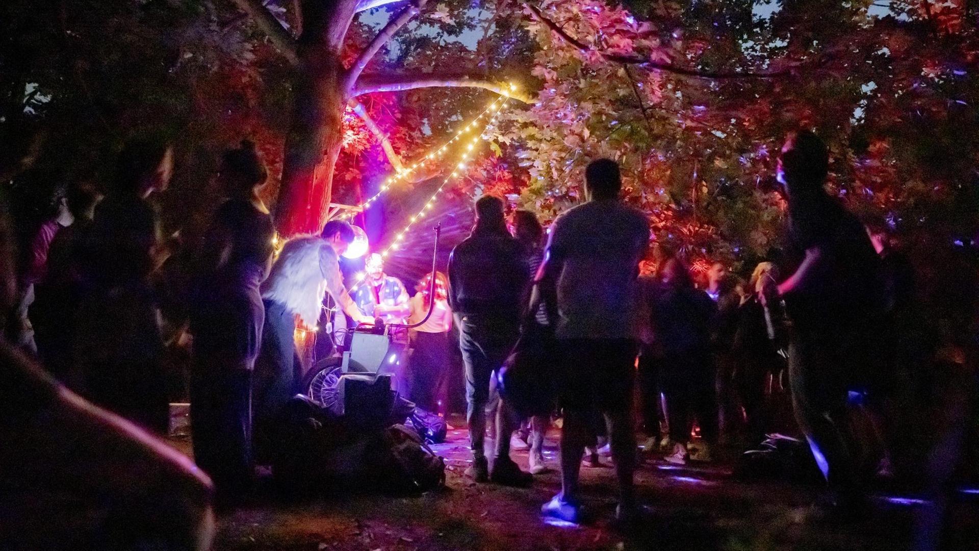 Menschen feiern nachts im Berliner Volkspark Hasenheide eine Party.