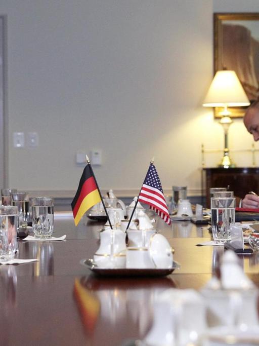 Annegret Kramp-Karrenbauer und Mark Esper sitzen sich an einem Tisch gegenüber, in der Mitte die beiden Flaggen.