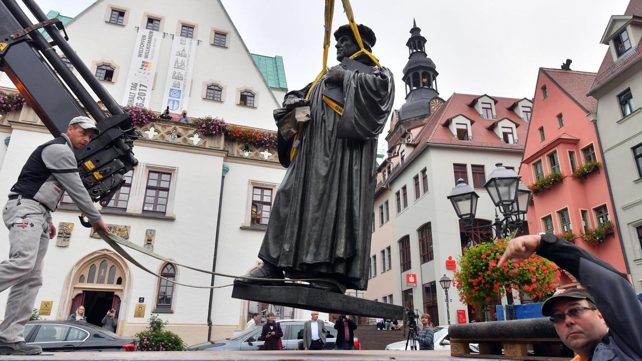 Mit einem Kran wird das Martin-Luther-Denkmal am 26.09.2016 auf dem Marktplatz in Eisleben (Sachsen-Anhalt) auf den Sockel gehoben.