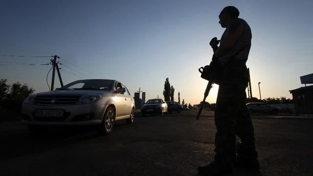 Ein prorussischer Kämpfer kontrolliert Fahrzeuge in der Stadt Krasnopartizansk an der ukrainisch-russischen Grenze.