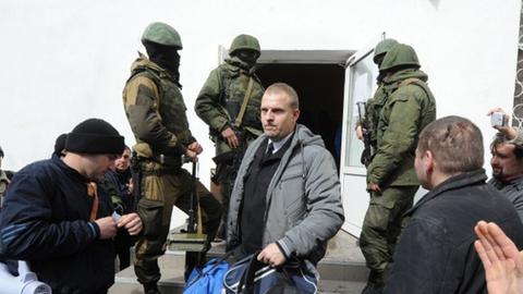 Ein ukrainischer Offizier verlässt unter den Augen russischer Soldaten das Hauptquartier der ukrainischen Marine in Sewastopol.