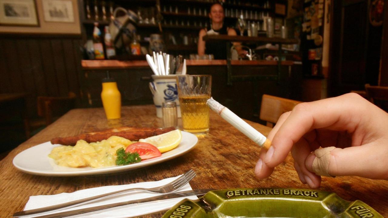 Eine Hand hält in einer Speisegaststätte  eine Zigarette 