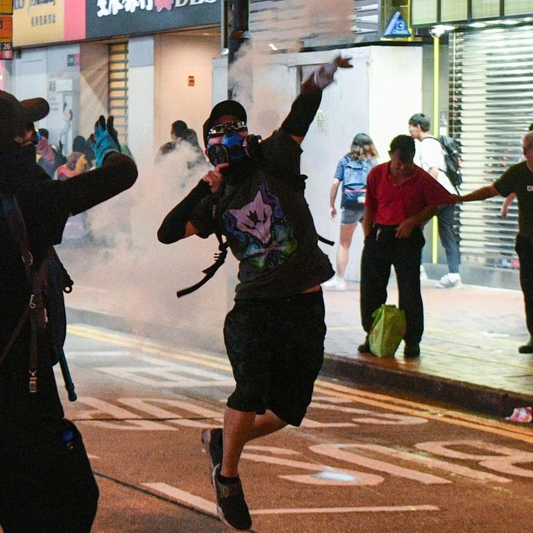 Demonstranten mit Atemmasken in einer Geschäftsstraße in Hongkong. 