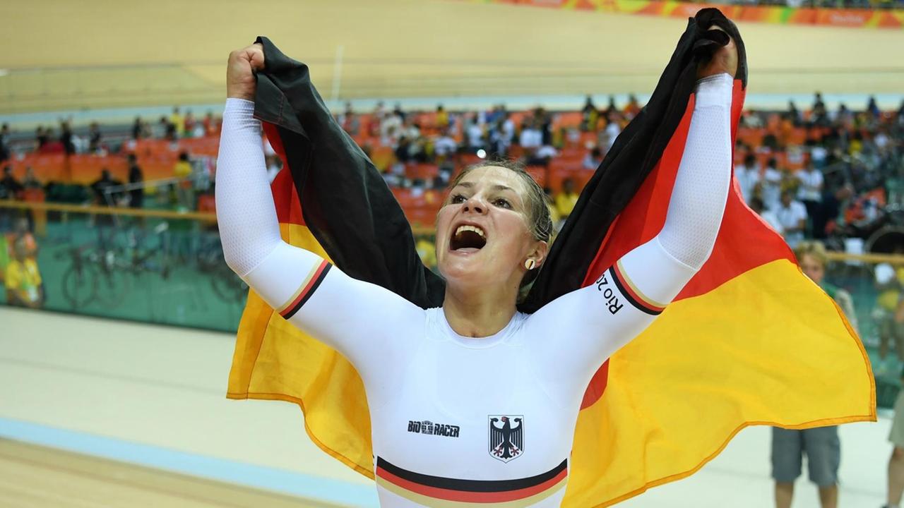 Vier Jahre nach ihrem überraschenden Olympiasieg im Teamsprint gewinnt Kristina Vogel wieder Gold - jubelnd hält sie eine deutsche Fahne in die Höhe