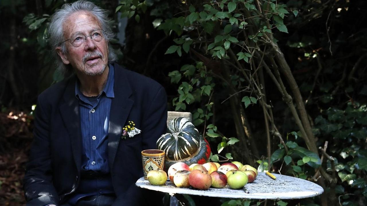 Der Schriftsteller Peter Handke sitzt an einem kleinen runden Tisch mit Äpfeln in seinem Garten in Chaville in der Nähe von Paris.