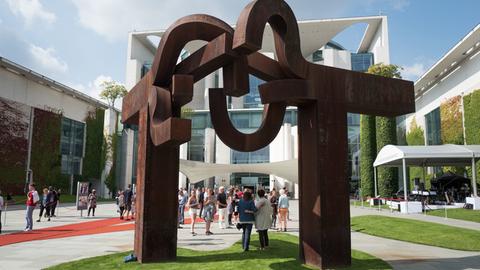 Besucher lassen sich beim Tag der offenen Tür der Bundesregierung im Bundeskanzleramt in Berlin unter der Skulptur "Berlin" des Künstlers Eduardo Chillida fotografieren.