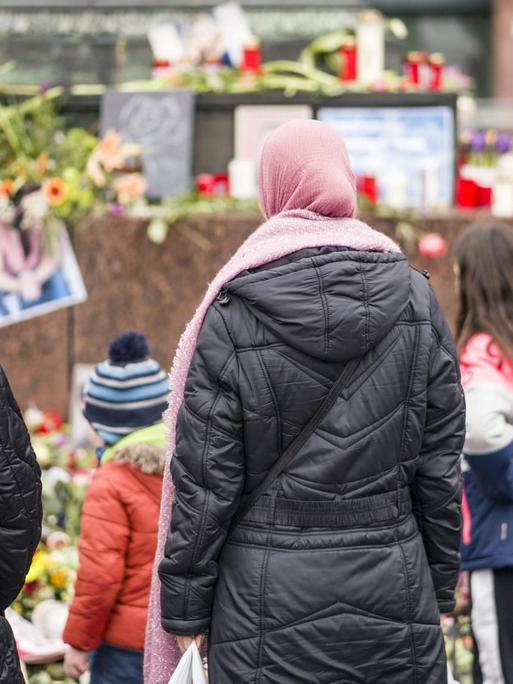 Menschen stehen in Hanau am Denkmal der Brüder Grimm auf dem Marktplatz, wo Bürger mit Blumen, Plakaten und Kerzen ihre Trauer zum Ausdruck bringen.