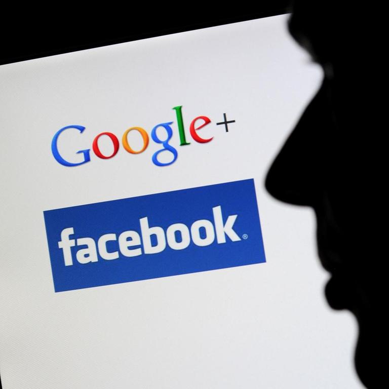 Die Silhouette eines Mannes zeichnet sich vor einem Computerbildschirm mit den Logos von Google+ und Facebook ab.