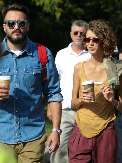 Mehrere Menschen laufen mit einem Kaffeebecher in der Hand durch einen Moskauer Park.
