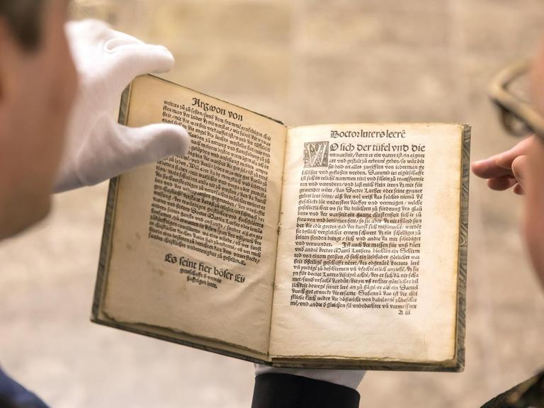 Die Idee der Streitschrift ist alt: Zwei Männer betrachen die anti-lutherische Streitschrift von Thomas Murner von 1520.