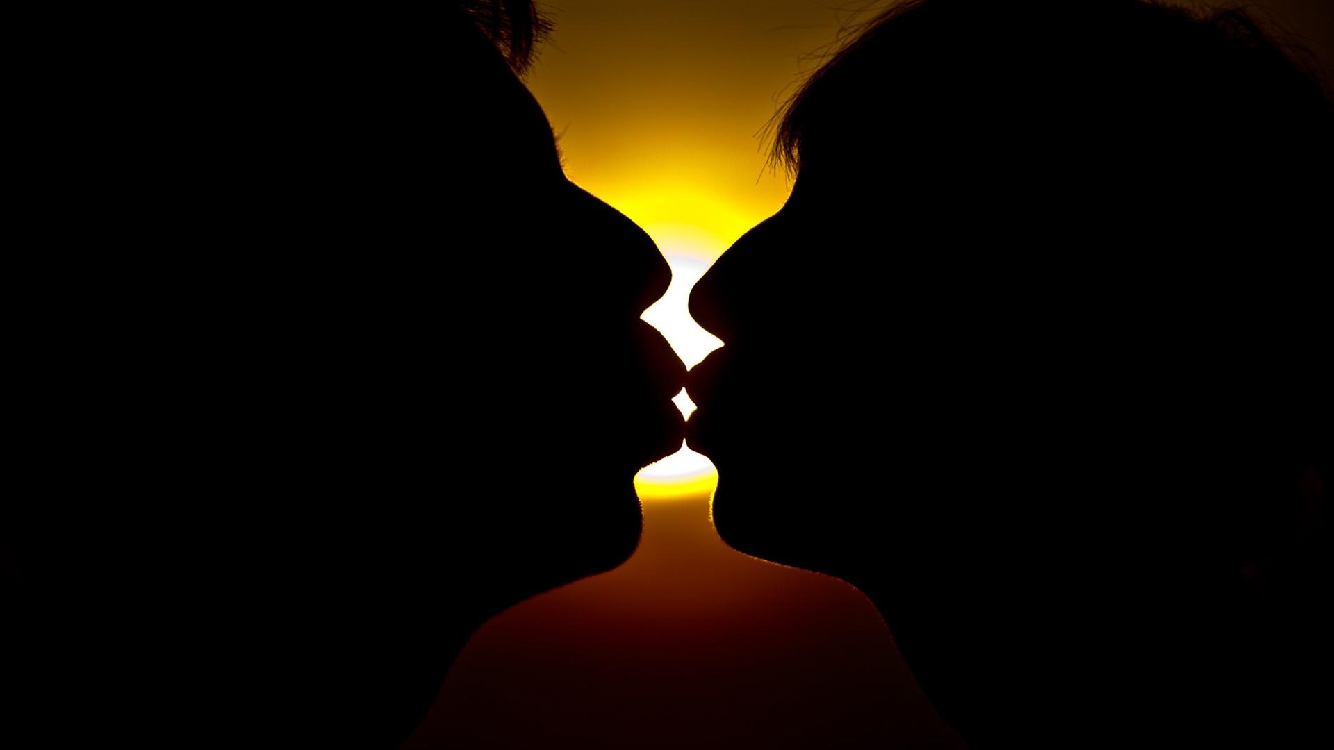Ein Mann und eine Frau küssen sich im Sonnenuntergang.