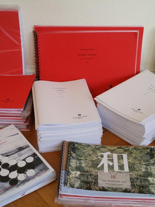 Eine Zusammenstellung von Druckausgaben des Verlags Neue Musik Berlin auf einem Tisch liegend.
