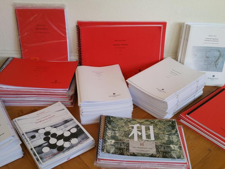 Eine Zusammenstellung von Druckausgaben des Verlags Neue Musik Berlin auf einem Tisch liegend.