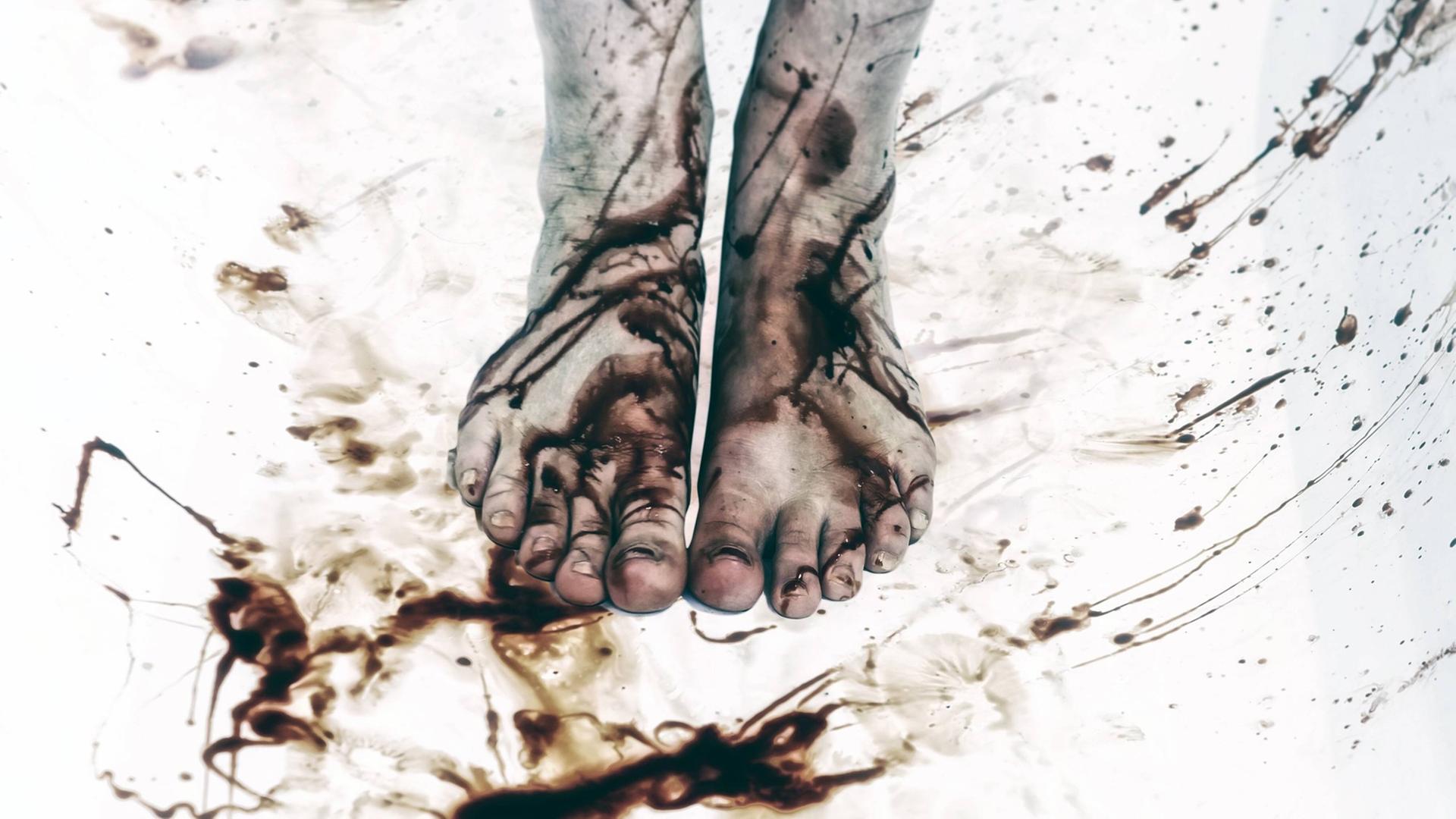 Nackte Füße, auf denen Blutspritzer zu sehen sind.