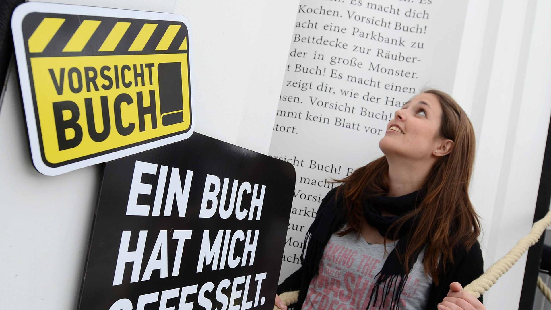 Eine Frau posiert am 13.03.2013 auf der Buchmesse Leipzig (Sachsen) an einem Stand zur Kampagne des Börsenvereins des Deutschen Buchhandels "Vorsicht Buch". Mit der auf drei Jahre angelegten Kampagne wollen Buchhändler, Verlage und die Zwischenbuchhändler