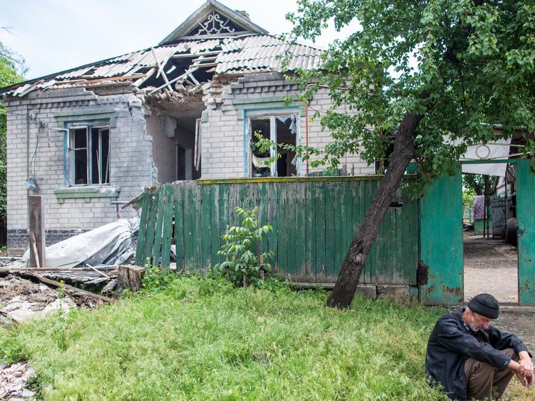 Ein Mann sitzt am Stadtrand von Slowjansk vor seinem zerstörten Haus.