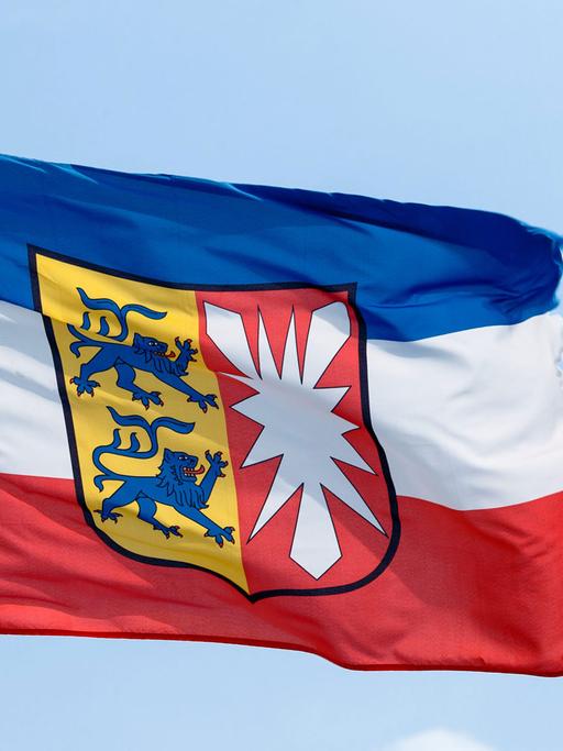 Die Landesflagge von Schleswig-Holstein mit seinem Wappen