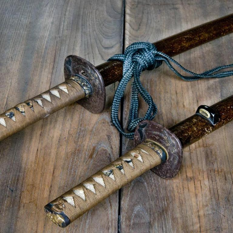 Zwei traditionelle japanische Schwerter liegen auf einer Holzfläche