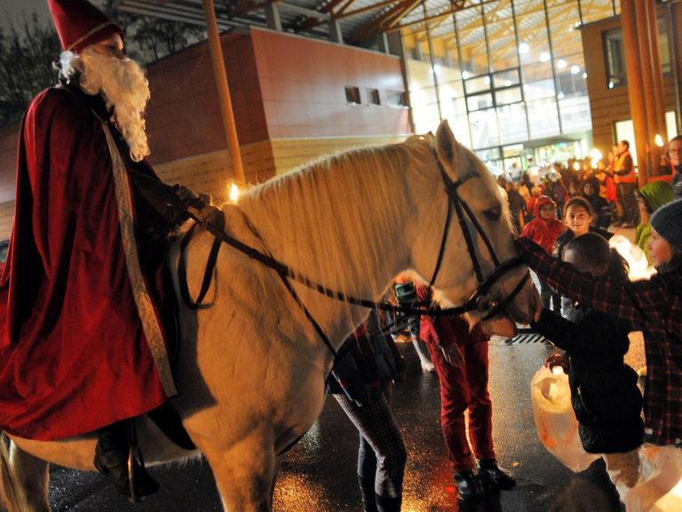Kinder begrüßen am 07.11.2013 in Köln (Nordrhein-Westfalen) beim Martinszug der Montessori Grundschule Am Pistorhof den Darsteller des Heiligen Martin und sein Pferd.