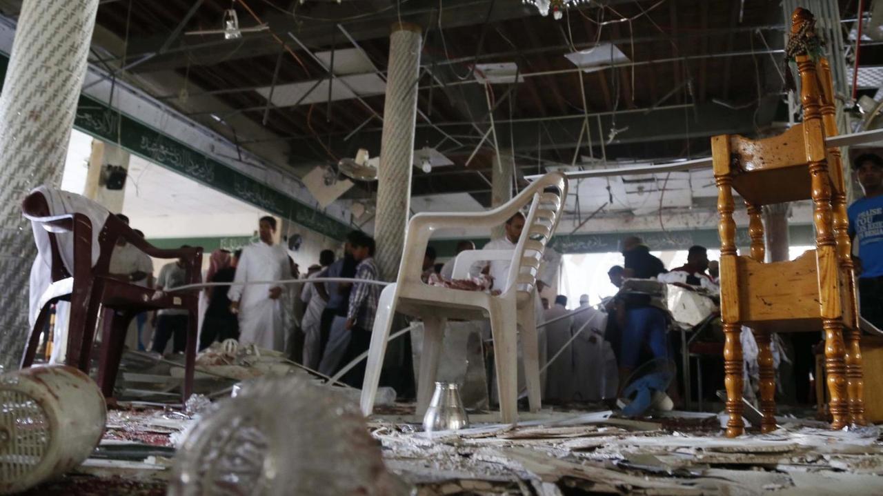 Der Innenraum der Moschee in Katif ist durch den Anschlag völlig zerstört; Menschen durchsuchen die Trümmer.