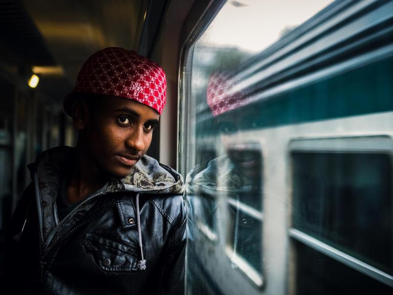 Beschreibung:Meron aus Eritrea blickt am 19.08.2015 im Zug von Rom nach Bozen (Italien) aus dem Fenster. Auf der Flucht vor Hunger Krieg und Verfolgung suchen viele Flüchtlinge das Glück in Europa