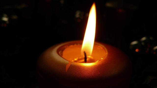 Brennende Kerze vor schwarzem Hintergrund