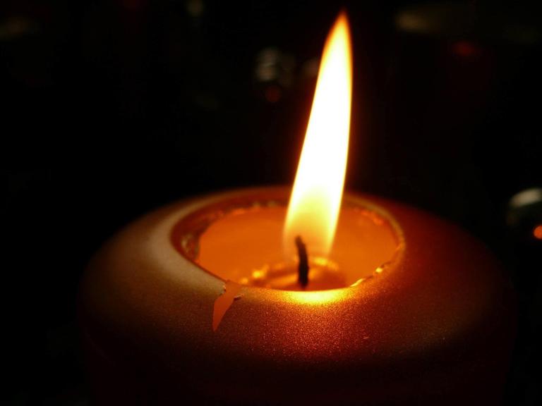 Brennende Kerze vor schwarzem Hintergrund