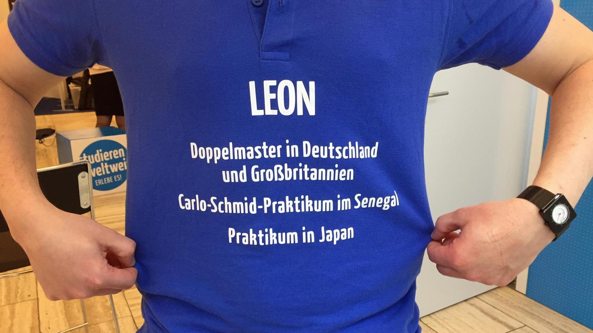 Die Aufschrift eines blauen T-Shirts zeigt: Leon - Doppelmaster in Deutschland und Großbritannien, Carlo-Schmid-Praktikum im Senegal - Praktikum in Japan