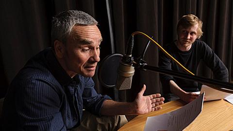 Aufnahmen in einem Studio zum Hörspiel "Oh ist das Morrissey" mit Ingo Hülsmann und Benjamin Kramme sitzend an einem Tisch mit Mikrofon