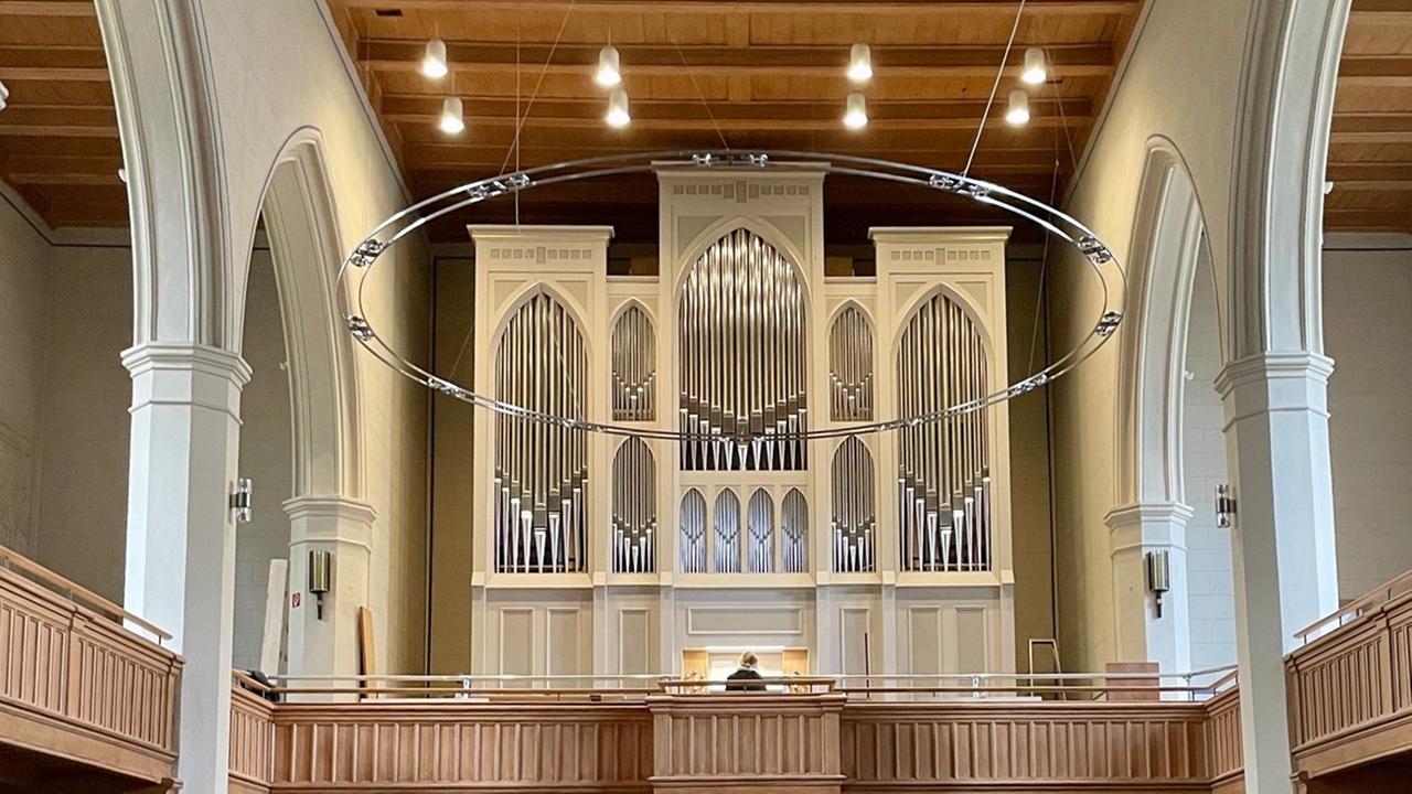 Blick auf einen elegant-schlichten Orgelprospekt mit glänzenden Orgelpfeifen in einer Kirche mit flacher Holzdecke.