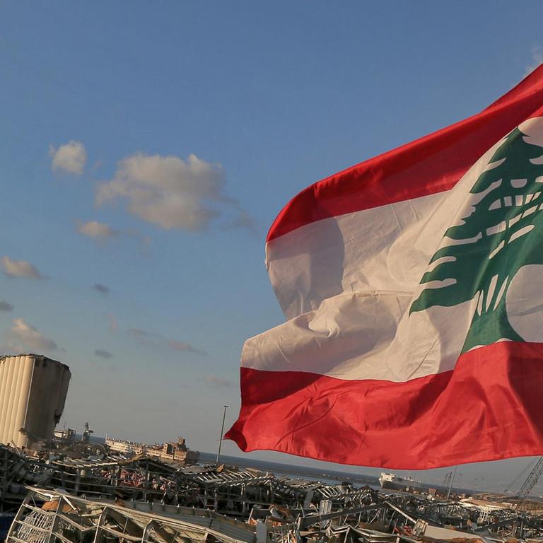 Eine libanesische Flagge weht in der Nähe der Stelle, an der eine massive Explosion den Hafen von Beirut in die Luft sprengte