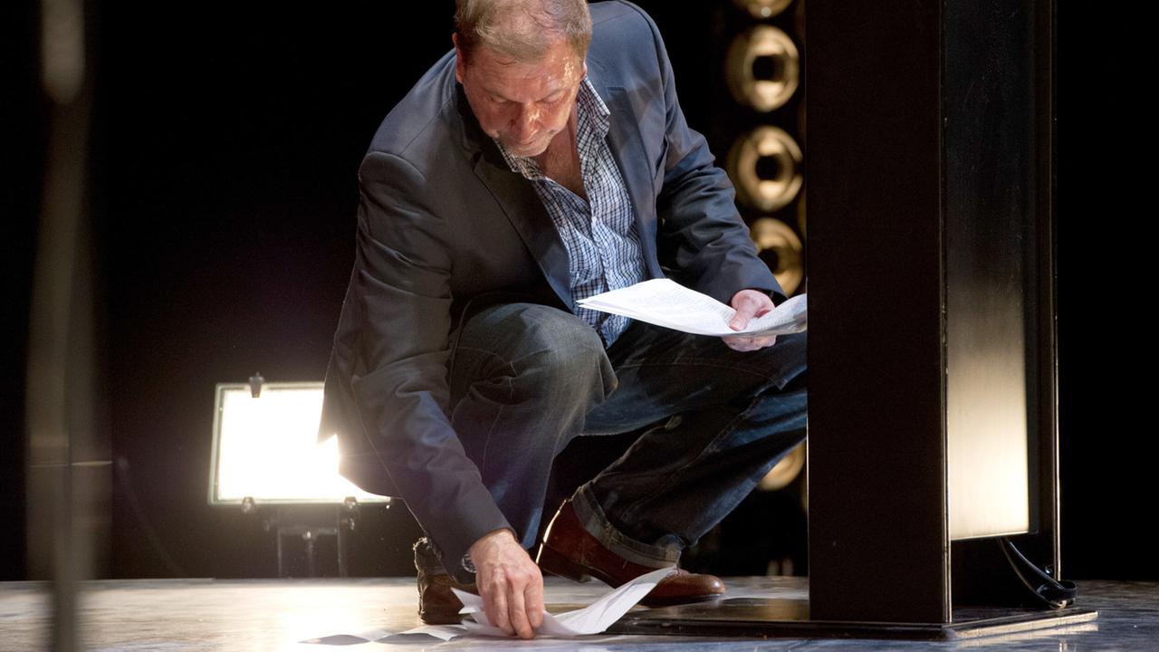 Rene Pollesch sammelt während der Verleihung des Theaterpreises die heruntergefallenen Blätter seines Redemanuskripts vom Boden auf.