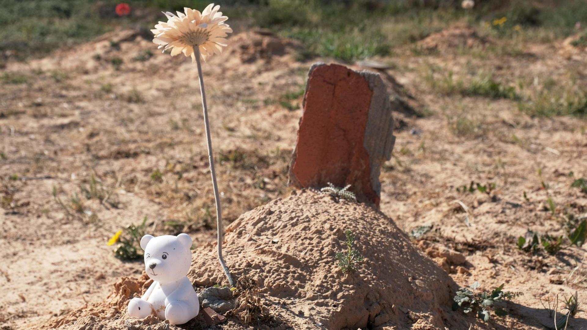 Ein kleines Grab mit Blume und Teddy auf dem "Friedhof des Unbekannten"