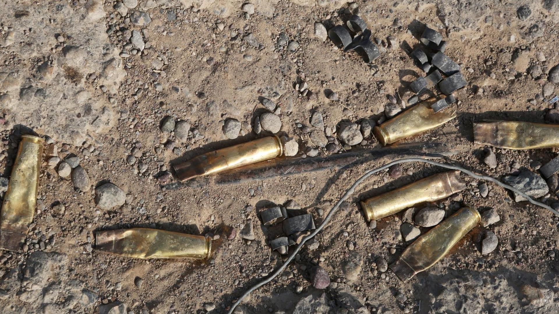 Aufsicht auf benutzte Patronenhülsen im grauen Sand.