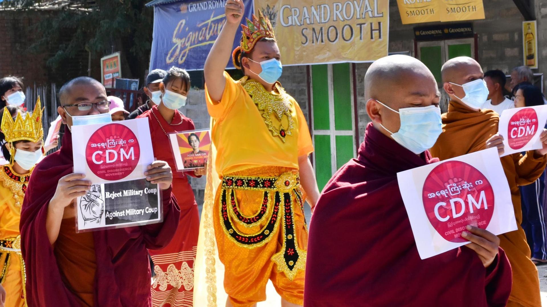 Mönche nehmen an einem Protestmarsch teil und halten Schilder mit der Aufschrift "CDM - Reject military coup" (Bewegung für zivilen Ungehorsam (CDM) - Militärputsch ablehnen).