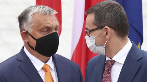 Mateusz Morawiecki (r), Premierminister von Polen, trägt einen Mundschutz und begrüßt Viktor Orban, Premierminister von Ungarn, ebenfalls mit Mundschutz.