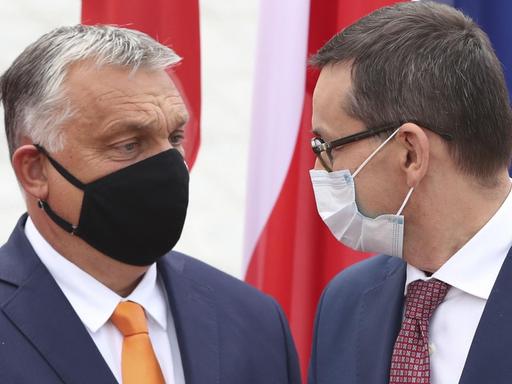 Mateusz Morawiecki (r), Premierminister von Polen, trägt einen Mundschutz und begrüßt Viktor Orban, Premierminister von Ungarn, ebenfalls mit Mundschutz.