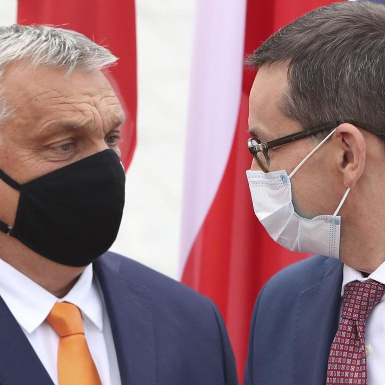 Mateusz Morawiecki (r), Premierminister von Polen, trägt einen Mundschutz und begrüßt Viktor Orban, Premierminister von Ungarn, ebenfalls mit Mundschutz.