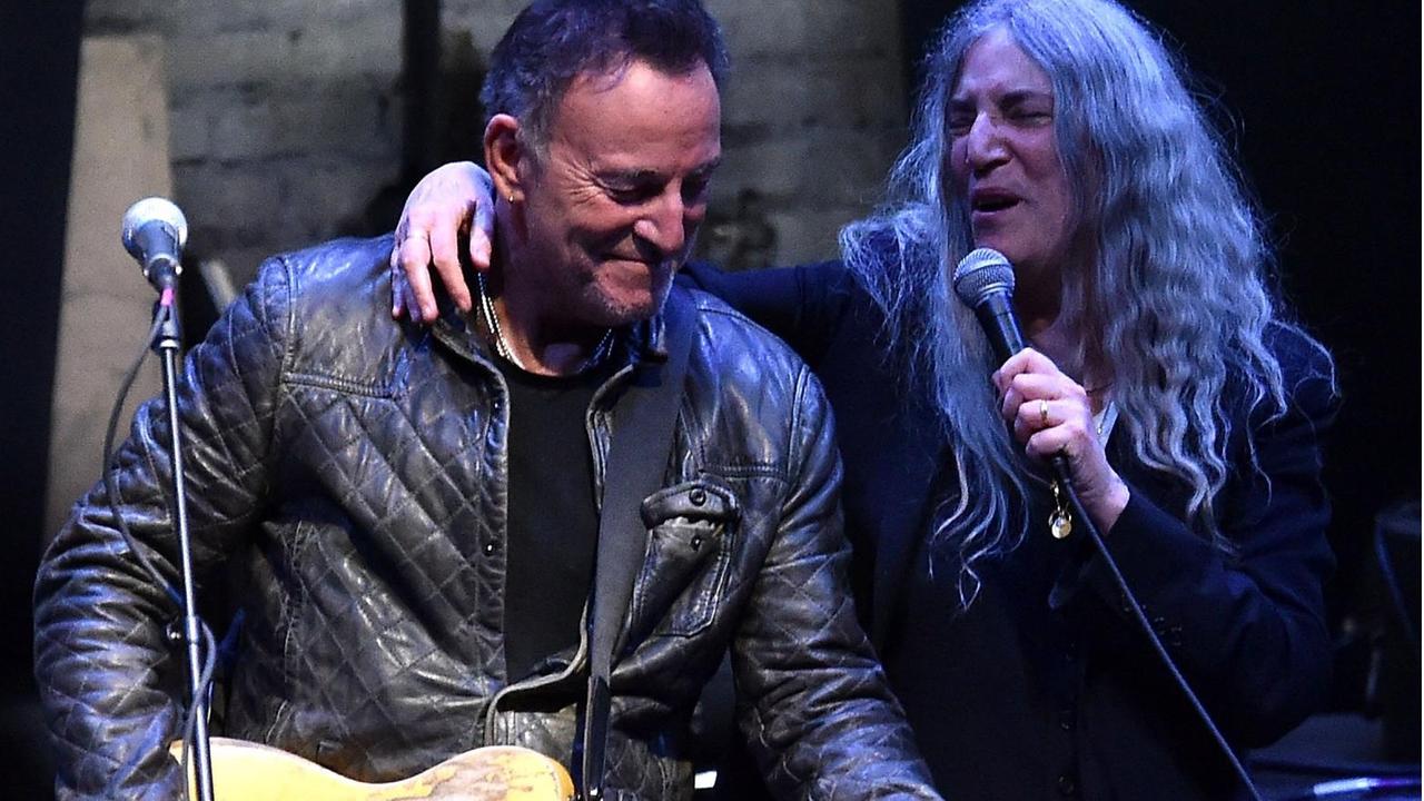 Bruce Springsteen wird beim Gitarrespielen von Patti Smith umarmt.