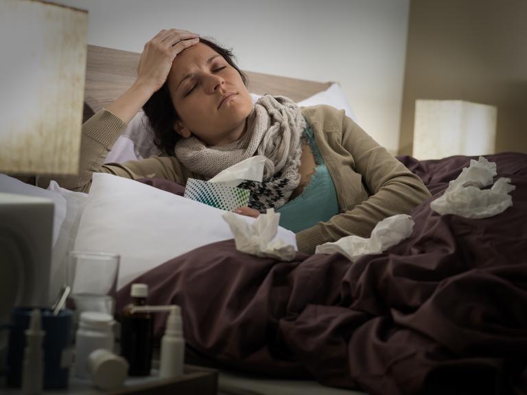 Eine Frau liegt krank im Bett.