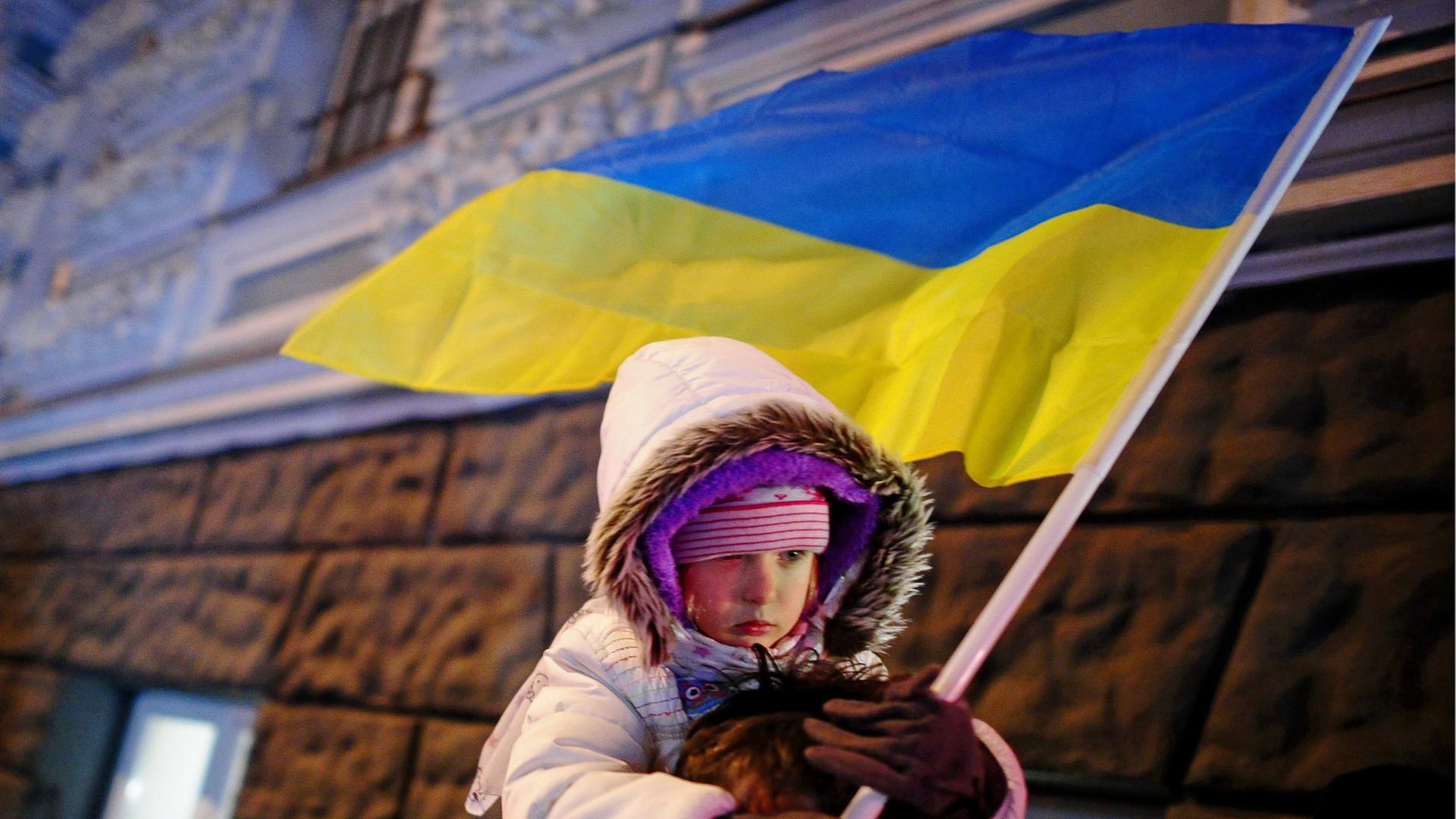 Kind mit ukrainischer Flagge auf der Schulter seines Vaters