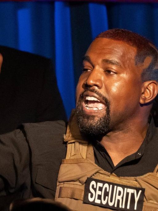 Der US-amerikanische Rapper Kanye West begrüßt in einer Weste der Security seine Anhänger in South Carolina bei einer Veranstaltung im Rahmen der anstehenden Präsidentschaftswahlen 2020